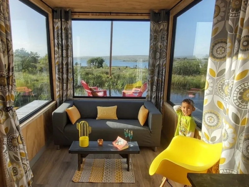 Tiny Container House en el lago costero de Irlanda - Se dispuso el living en el rincon más iluminado de la casa.