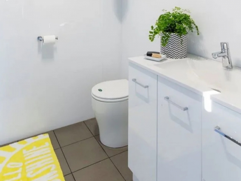 Casa contenedor con estilo por menos de 50.000 - Predominio del blanco en el baño equipado con lavabo con mueble, inodoro y lluvia.