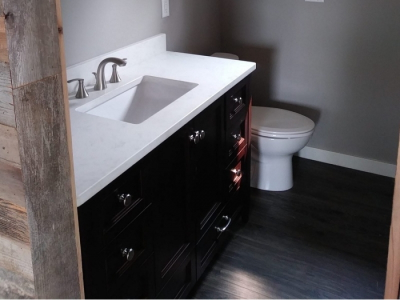 Contenedor de Lux Inicio - El lavabo con encimera blanca y mueble de madera color negro se suma a la elegancia del baño