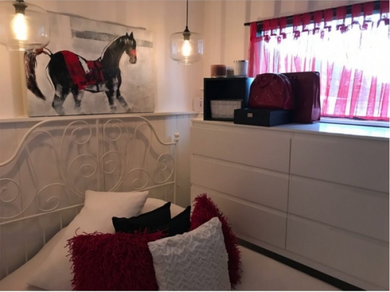 Ella convirtió un contenedor marítimo en una casa de campo - Este es el segundo dormitorio con detalles en rojo y muebles de color blanco.