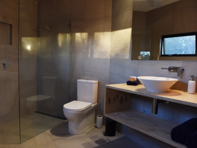 Hideaway Litchfield - La transformación de un contenedor de marítimo en una hermosa casa en Australia - Un moderno baño con ducha con pared de vidrio.