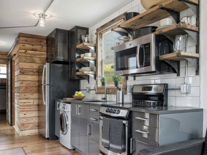Una casa container marítimo con decoración moderna y todo lo que precisa para vivir confortablemente - Cocina moderna con estantes de madera e hierro.