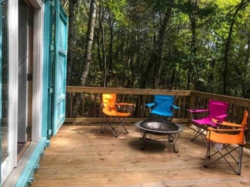 Casa de contenedor marítimo sustentable en Fort Payne, Alabama - Coloridos sillones invitan a descansar y disfrutar en la terraza de madera.
