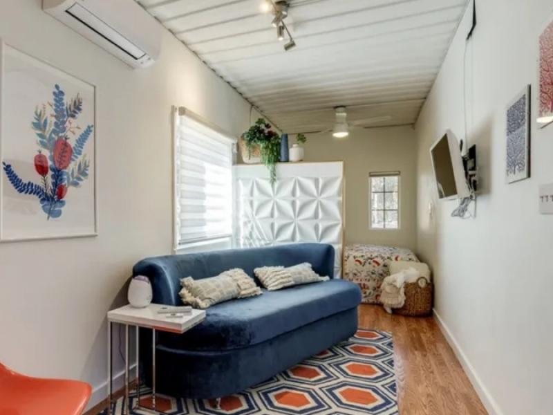 Elegante casa contenedor con combinación de blanco y madera de Texas - El azul del aterciopelado sofá se destaca en el espacio.