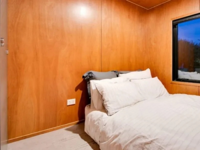 Casa contenedor convertida para ser subastada con fines benéficos - Paredes color madera en el dormitorio.