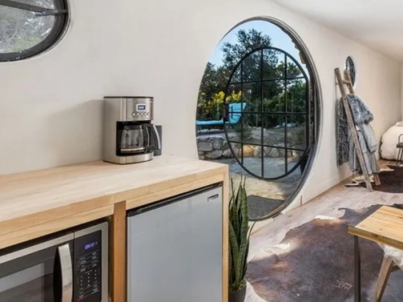 Encantadora casa pequeña en contenedor estilo Hobbit - Encimera de madera con bajo mesada, horno microondas y mini refrigerador en la cocina.