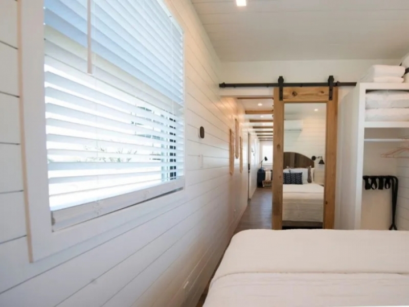 Casa contenedor pequeña pero de lujo con patio en el techo de Texas - Puerta corredera de madera con espejo en el dormitorio.