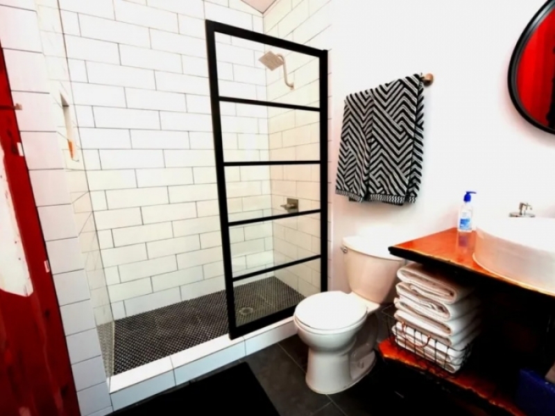 Casa contenedor del lado este - EE. UU. - Baño completo con ducha con azulejos personalizados.