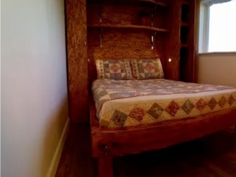 Casa de contenedores de envío de Utah - EE. UU. - El dormitorio con estantes empotrados en la pared y cama queen.